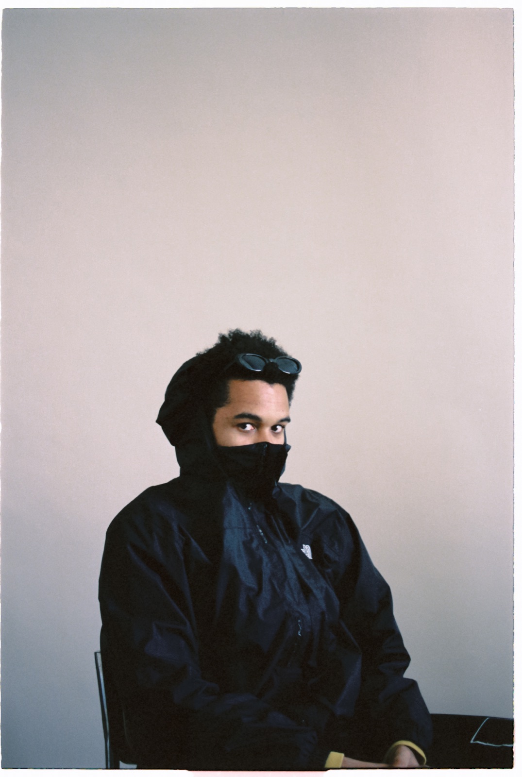 Yorke seated, hood up with sunglasses resting on his head