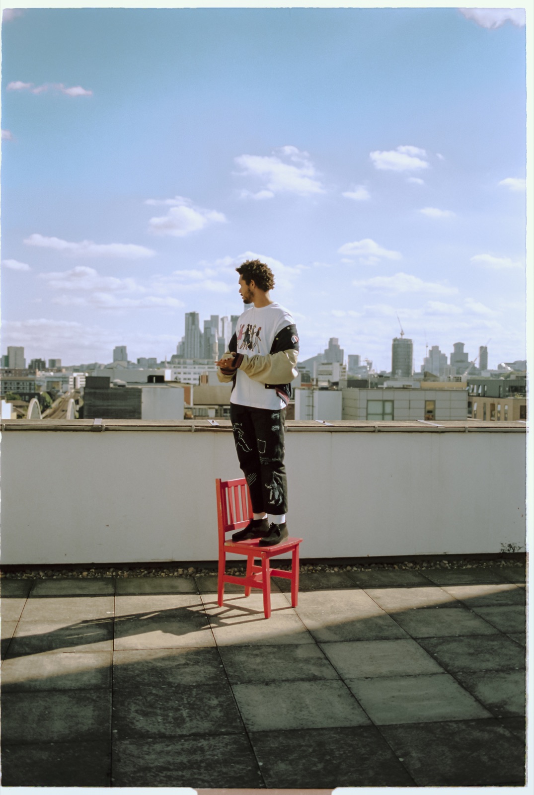 Yorke on a red chair on a rooftop against the London skyline