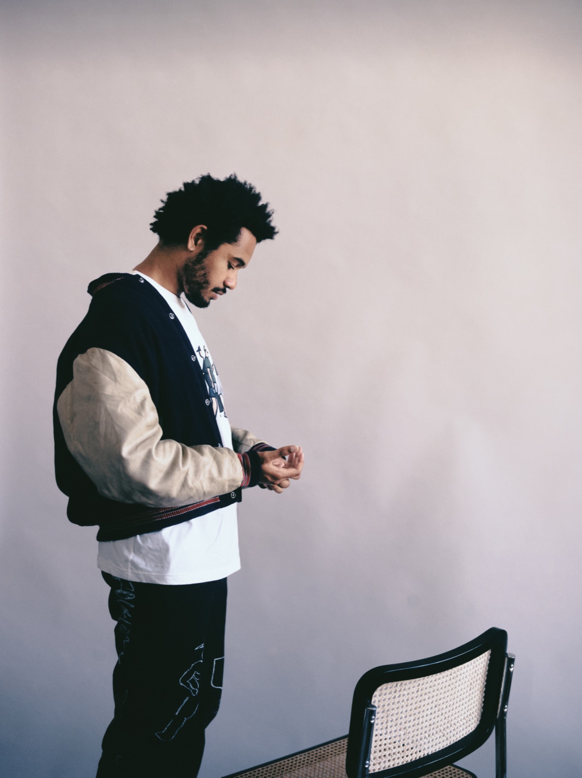 Yorke in profile in a varsity jacket against a plain wall
